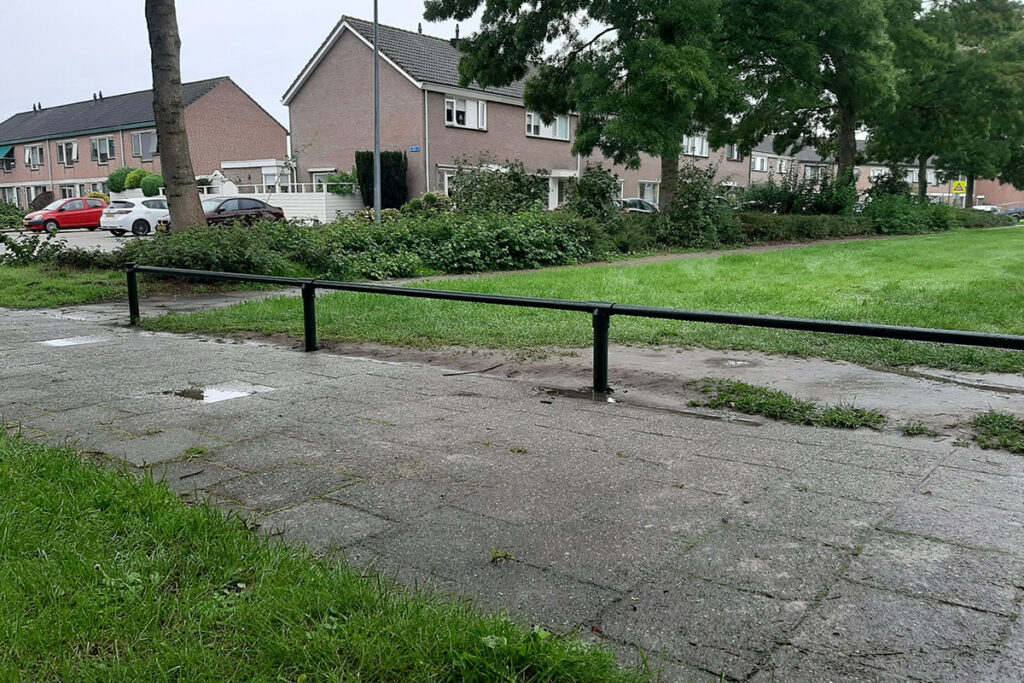Laag stalen plantsoenhekwerk langs een grasveld