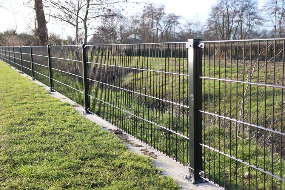 Groen dubbelstaafmat hekwerk langs een tuin